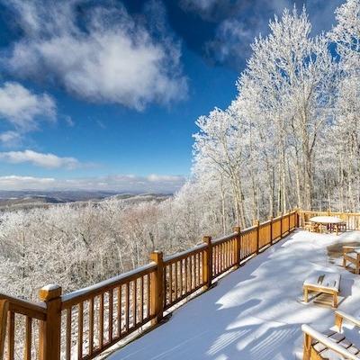 Snow-covered cabin deck with mountain views in Seven Devils, North Carolina